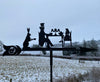 Alice in Wonderland Weathervane A whimsical tea party scene starring "Alice in Wonderland" figures is brought to life on the Alice in Wonderland Weathervane by Black Fox Metalcraft Ltd, set against a snowy landscape. This garden gift showcases durable ironwork, blending fantasy with the practicality of enduring craftsmanship.