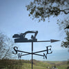 Doosan Excavator Weathervane The Doosan Excavator Weathervane by Black Fox Metalcraft Ltd elegantly displays cardinal directions against a rural landscape, with trees framing the scene under a clear blue sky. It features rust protection to ensure lasting durability.