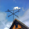 Elephant Weathervane A black metal Elephant Weathervane by Black Fox Metalcraft Ltd features a laser-cut elephant and calf design, perched on a rooftop with clear S, E, N, and W direction markers.