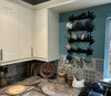 Wall mounted Mug Holder The kitchen corner has white cabinets, a marble counter, and patterned tiles. A Black Fox Metalcraft Ltd wall-mounted Mug Holder with a laser-cut fern design holds various mugs, while decorative plates and a ceramic hen add charm to the counter.