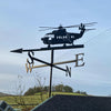 Helicopter Weathervane The Helicopter Weathervane by Black Fox Metalcraft Ltd features a graceful helicopter silhouette atop robust fixings, indicating North, South, East, and West against a charming rural backdrop.