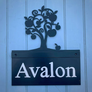 Metal house sign featuring laser cut apple tree photographed on wooden panel door