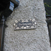 A rectangular "Belmont 1912" plaque by Black Fox Metalcraft Ltd is displayed on a textured wall, highlighting the refined look of their Metal Art Address Signs.