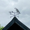 Hawk weathervane mounted to the wooden barge boards of a building.