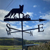 Fox weathervane with fern detailing, photographed against a blue sky.