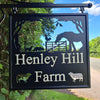 Hand painted hanging farm sign featuring sheep cut outs.