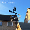 A Dancing Couple Weathervane by Black Fox Metalcraft Ltd is mounted on a roof against a clear blue sky, featuring silhouettes of two dancers atop directional markers. "Dancing Couple Weathervane" appears in the top left corner.