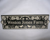 The Metal Art Address Sign by Black Fox Metalcraft Ltd features a rectangular black and white design with "Weston Jones Farm," decorative leaf patterns, and two bird silhouettes in an Art Nouveau style.