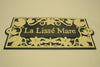 The Metal Art Address Signs by Black Fox Metalcraft Ltd feature a rectangular design with a Lily and Dragonfly border design. "La Lissé Mare" is hand painted on this address plaque.