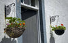 A pair of Manchester Bee hanging basket brackets mounted either side of our front door, hand forged by a Mancunian in Scotland!