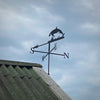 Weathervane featuring an Orca mounted to the end of a garage, photographed with blue sky background.