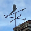 Pheasant weathervane mounted to the side of a chimney, with blue sky background