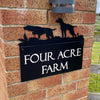 A brick pillar sign displays "Four Acre Farm," featuring Black Fox Metalcraft Ltd's Pointers House Sign with laser-cut dog breed silhouettes and a small top light fixture, offering rust protection for lasting charm.