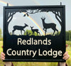 Hanging sign featuring three Roe Deer, with a dark sky and rainbow in the background of the photo.