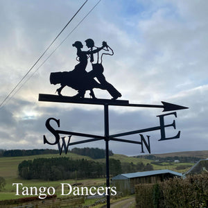 The Dancing Couple Weathervane by Black Fox Metalcraft Ltd features two dancers' silhouettes set against a cloudy sky, rural fields, and buildings. "Tango Dancers" appears in the lower left corner of the image.