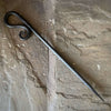 Hand forged fireside poker next to log burner