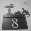 Metal house sign with cat and bird design.