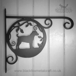 The Patterdale Dog Hanging Basket Bracket by Black Fox Metalcraft Ltd is an exquisite garden decoration, perfect for dog owners. It features a dog's silhouette surrounded by leaves and decorative scrolls.